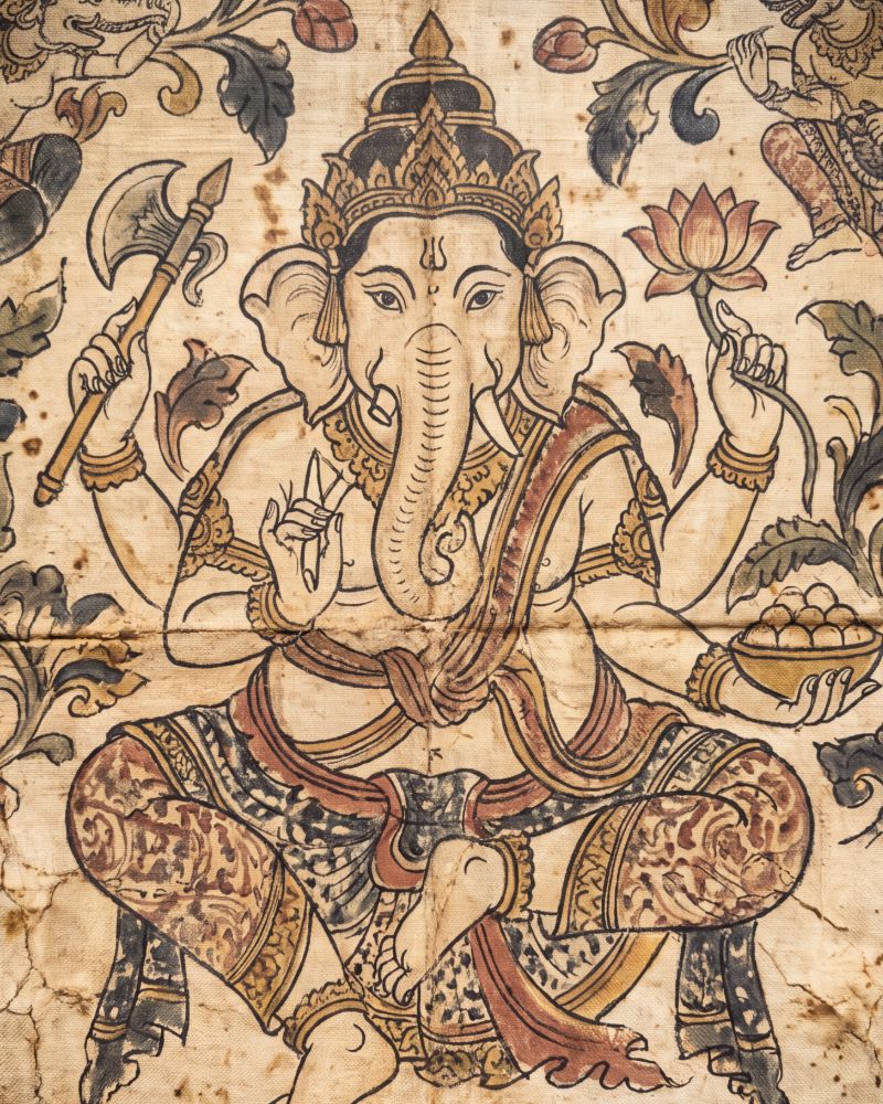 Painting on cloth of four-armed Ganesha seated cross-legged, holding an axe, a lotus and a bowl of sweets, among curling leaves