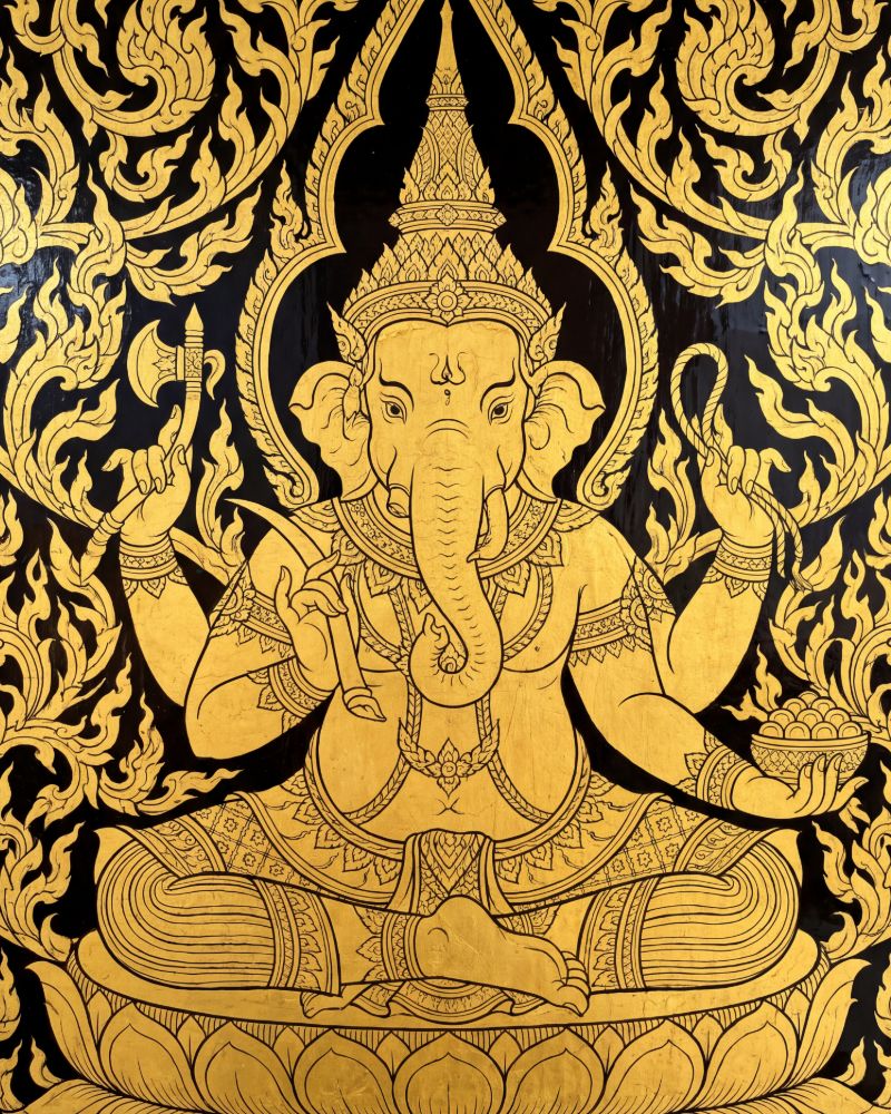 Gold on black lacquer painting of four-armed Ganesha seated on a lotus, holding an axe, a noose and a bowl of sweets, framed by flame-like Thai ornament