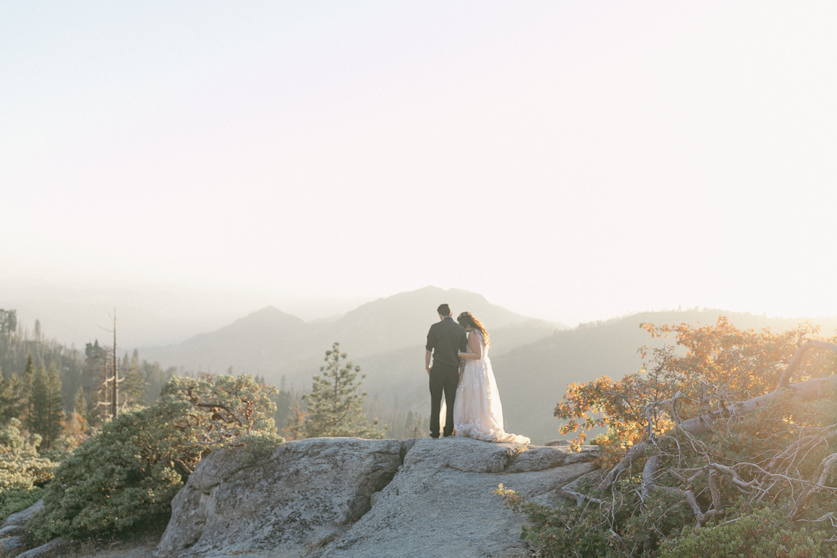 Couple on a granite overlook at sunset with Sierra foothills in the distance, Sequoia National Park